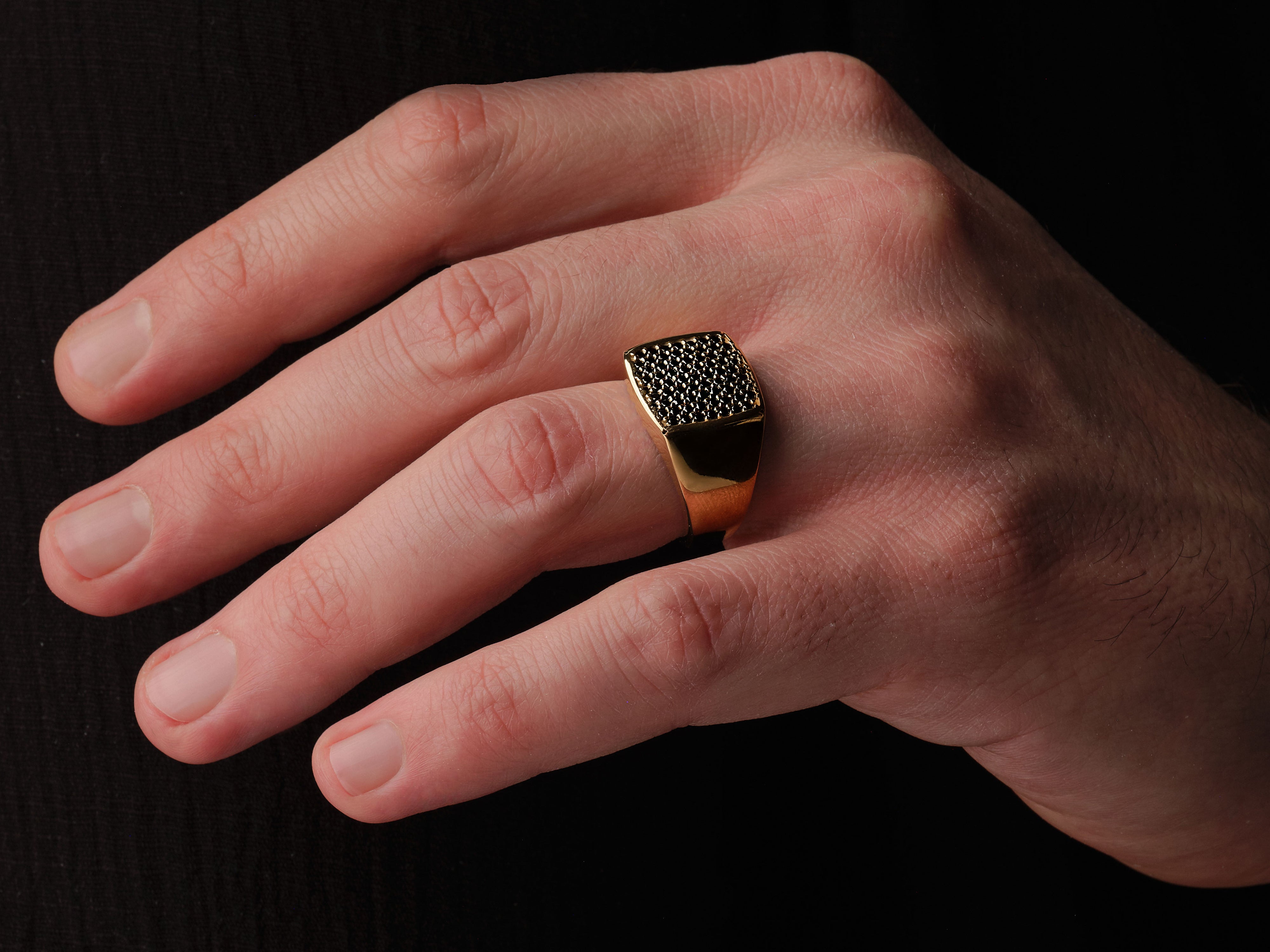 Gold signet ring with black diamonds on a man's finger