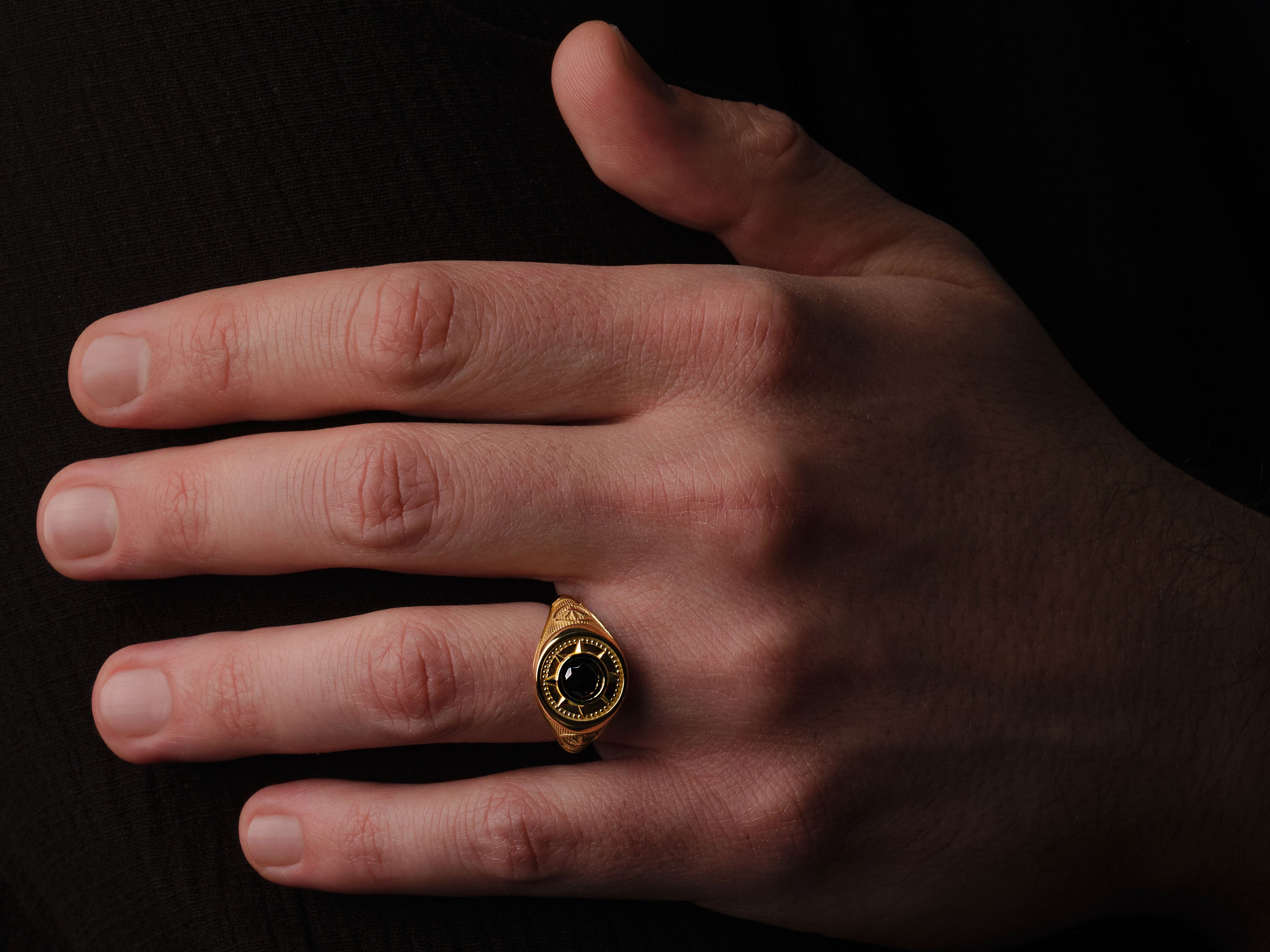 Gold signet ring with black stone on man's hand