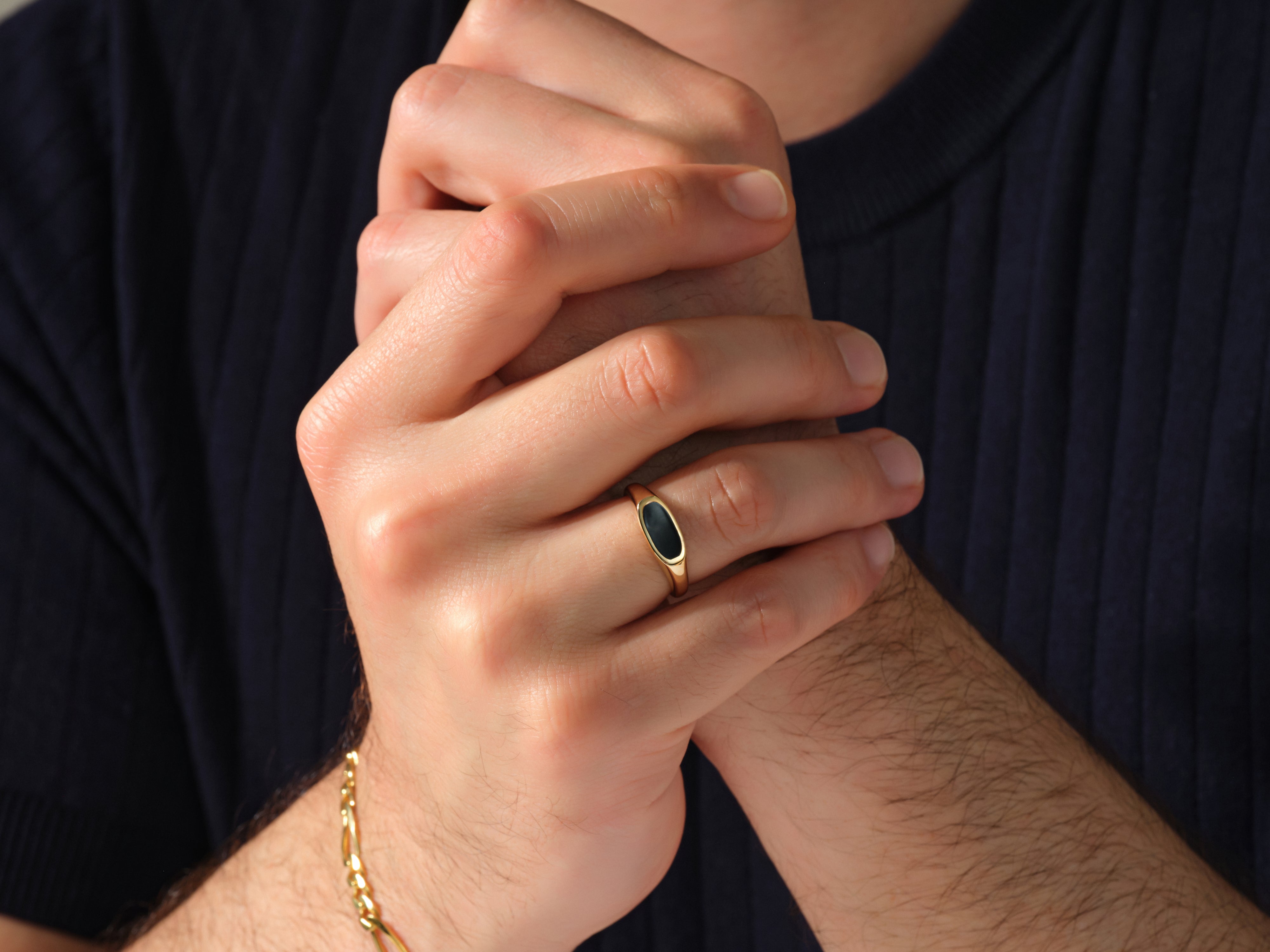 Gold signet ring with black stone on man's hand