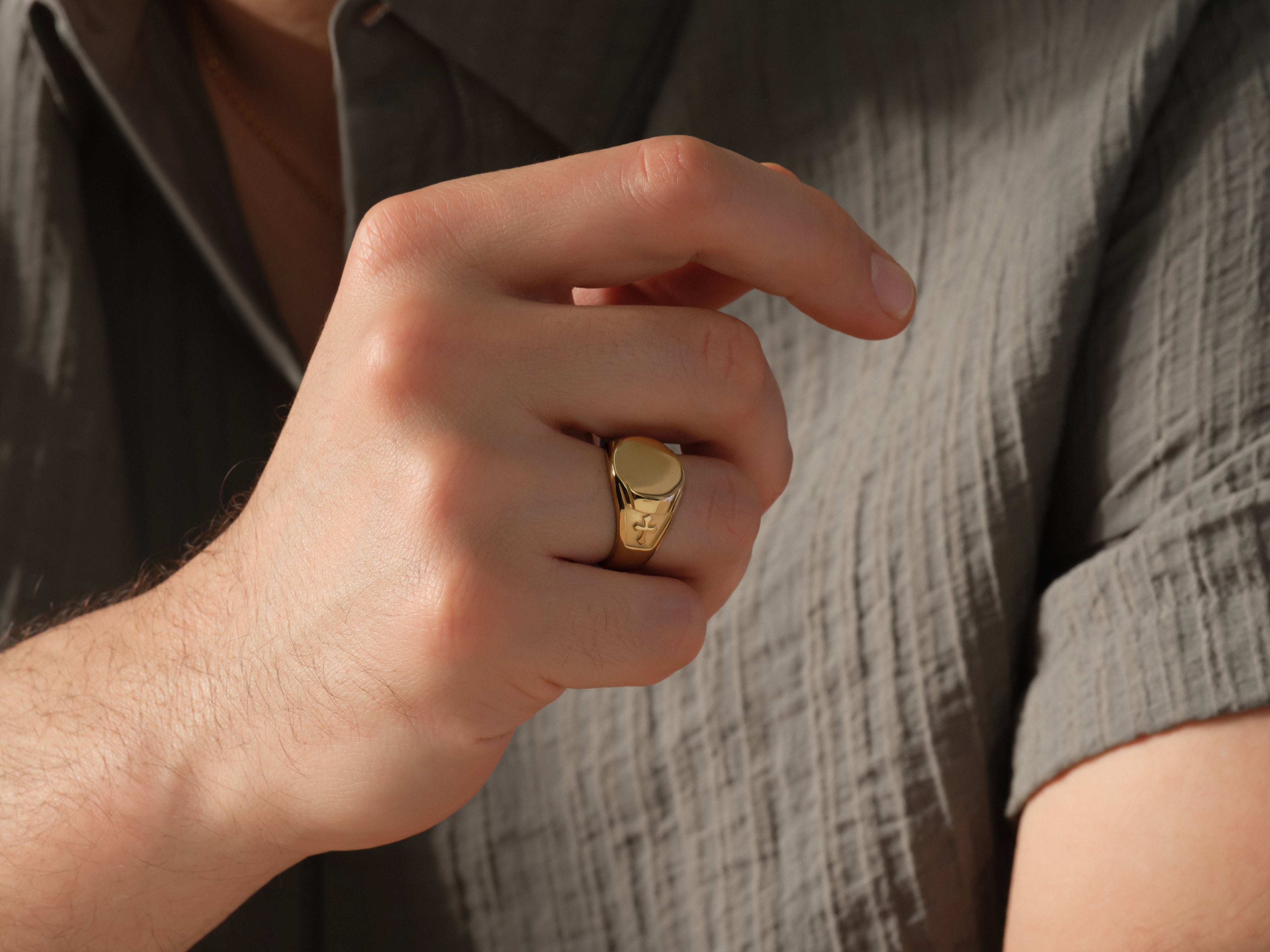 Gold signet ring with fleur-de-lis detail on hand