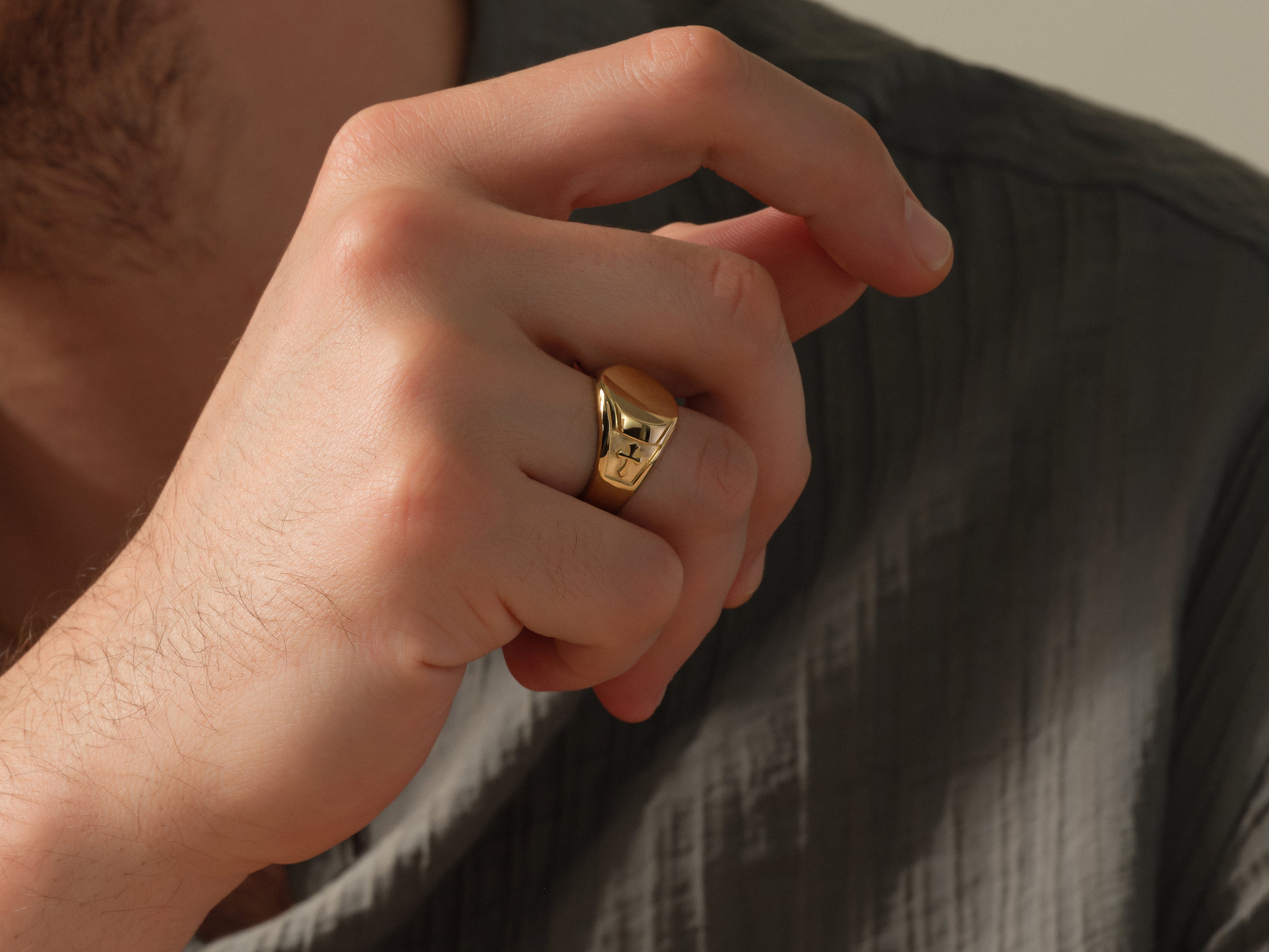 Gold signet ring on a man's finger, luxury jewelry
