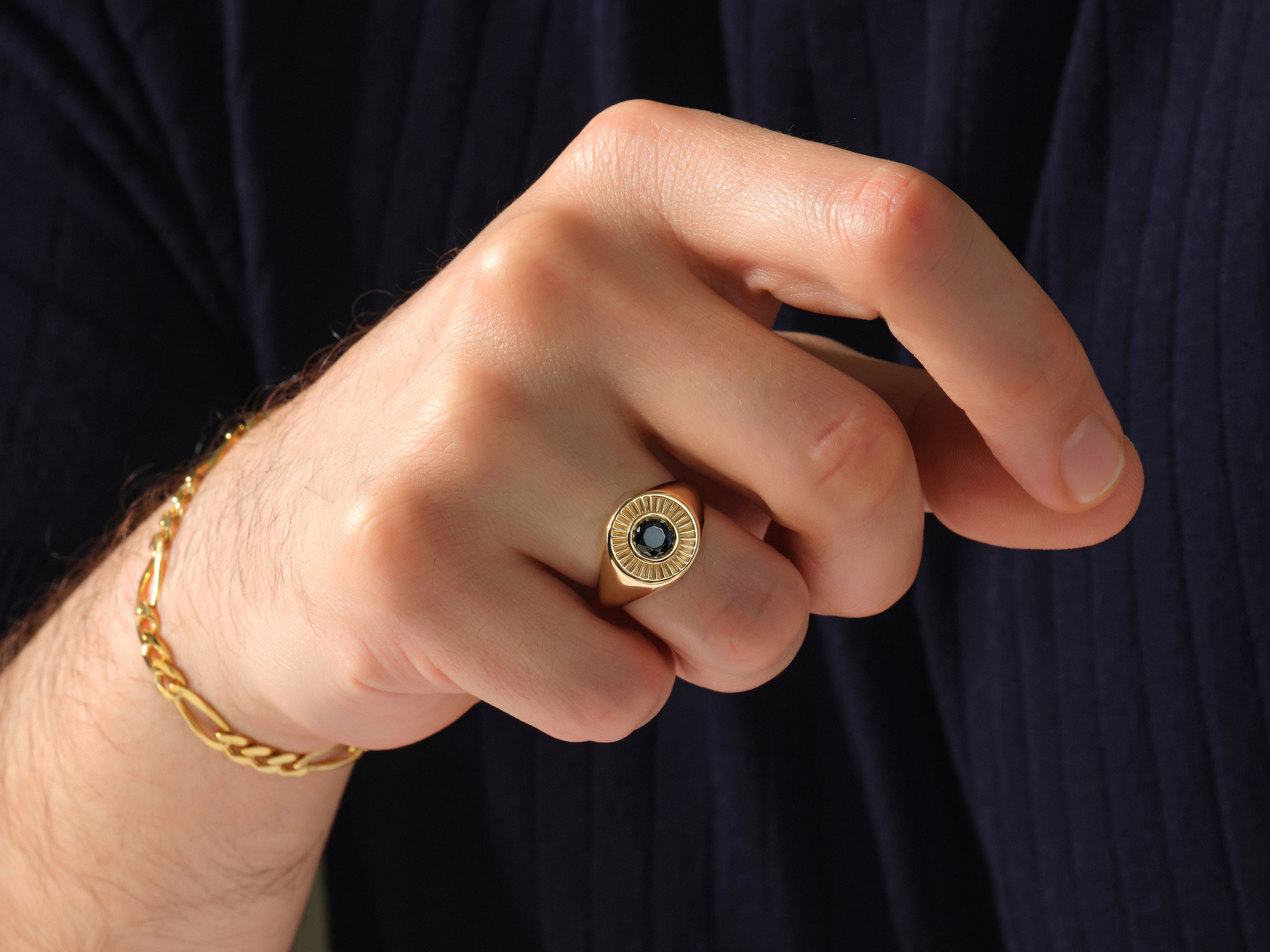 Gold signet ring with black stone and bracelet on hand