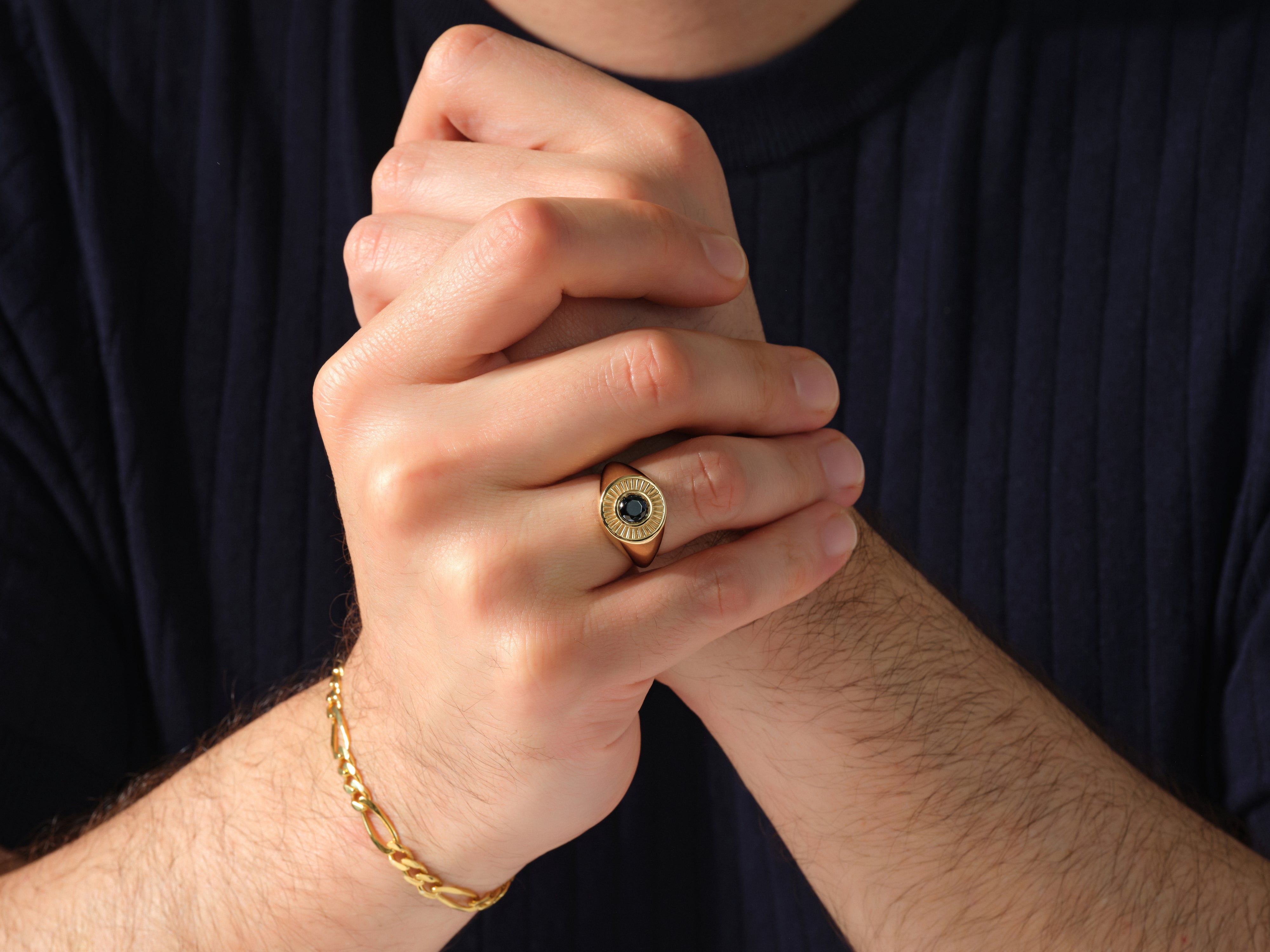 Gold signet ring with black stone and bracelet on man's hand