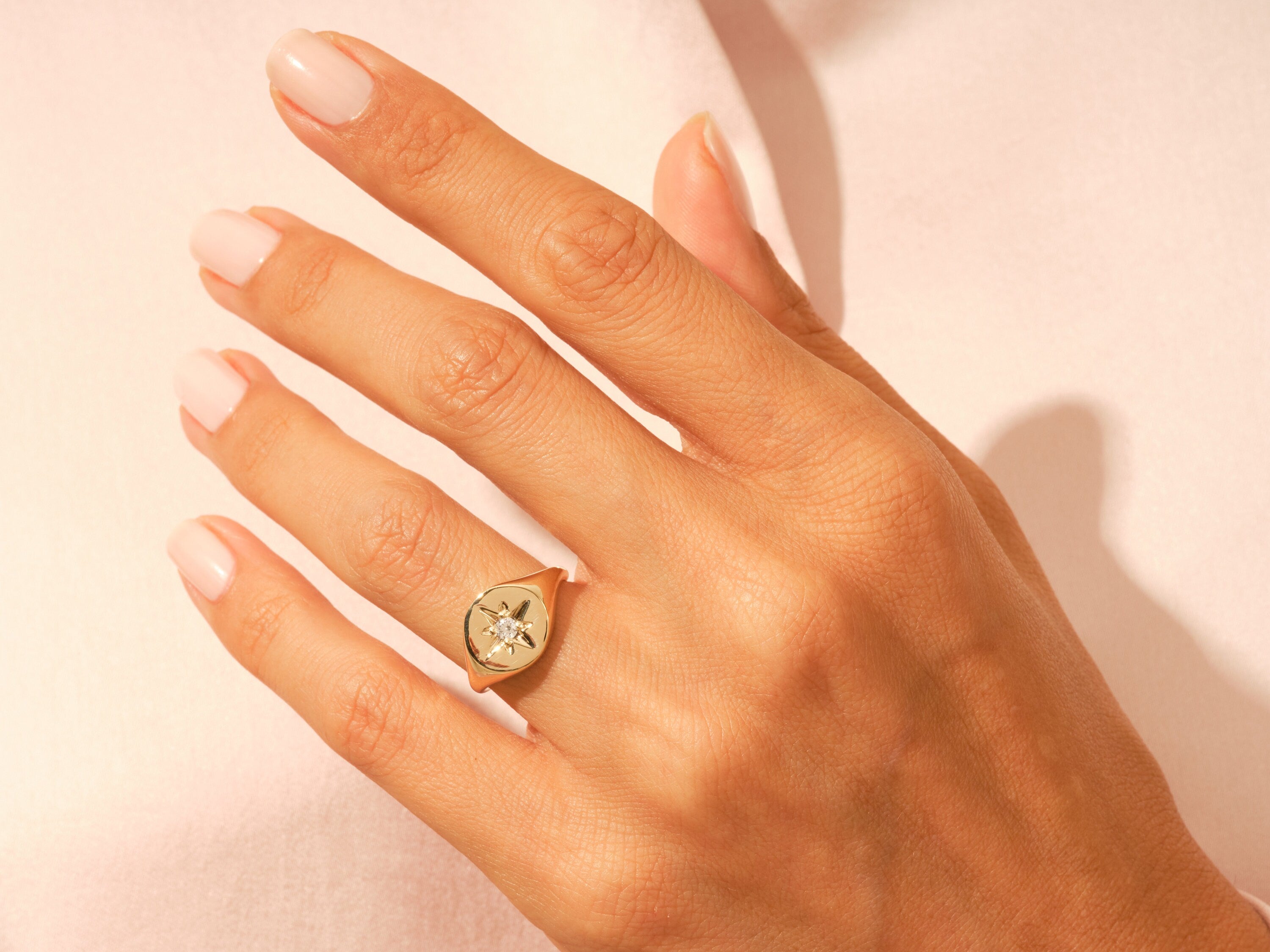 Gold signet ring with diamond starburst on a woman's hand