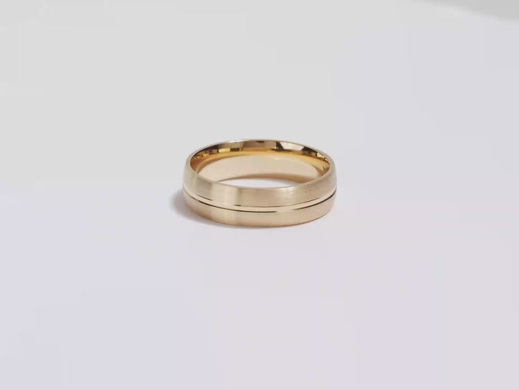 A video showing a yellow gold 6mm basic carved matte men's gold wedding band spinning on a white background