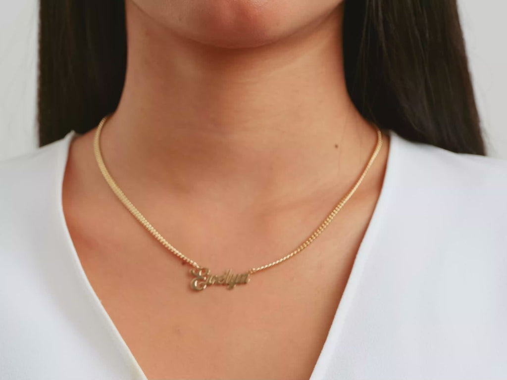 A video of a women model showing a yellow gold cuban chain bold name necklace on her neck