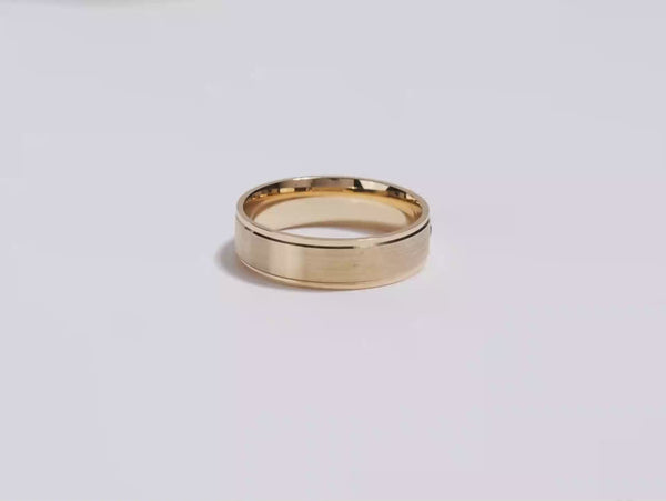 A video showing a yellow gold 6mm matte beveled flush setting men's diamond wedding band spinning on a white background.