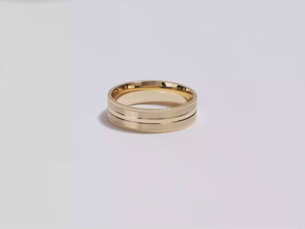 A video showing a yellow gold 6mm mid-beveled and matte milgrain men's gold wedding band spinning on a white background