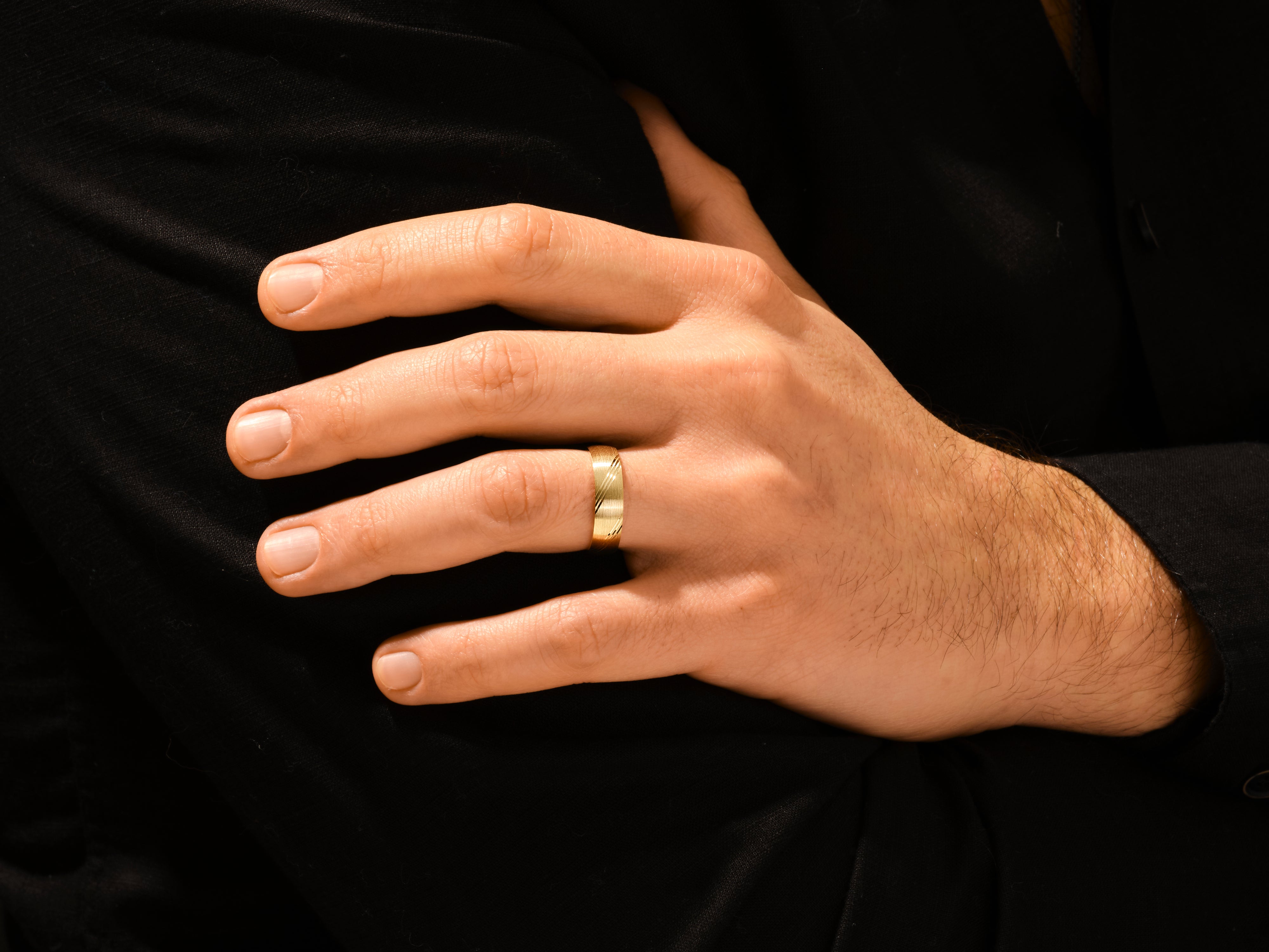 Gold ring with diagonal pattern on man's finger, jewelry