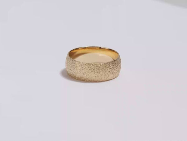 A video showing a yellow gold 8mm domed stardust men's wedding band spinning on a white background