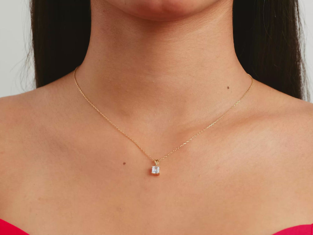 A video of a women model showing a yellow gold princess cut moissanite solitaire pendant on her neck