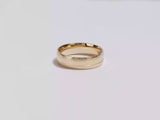A video showing a yellow gold 6mm ice matte grooved men's wedding band spinning on a white background