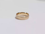 A video showing a yellow gold 6mm drop beveled hammered men's wedding band spinning on a white background.