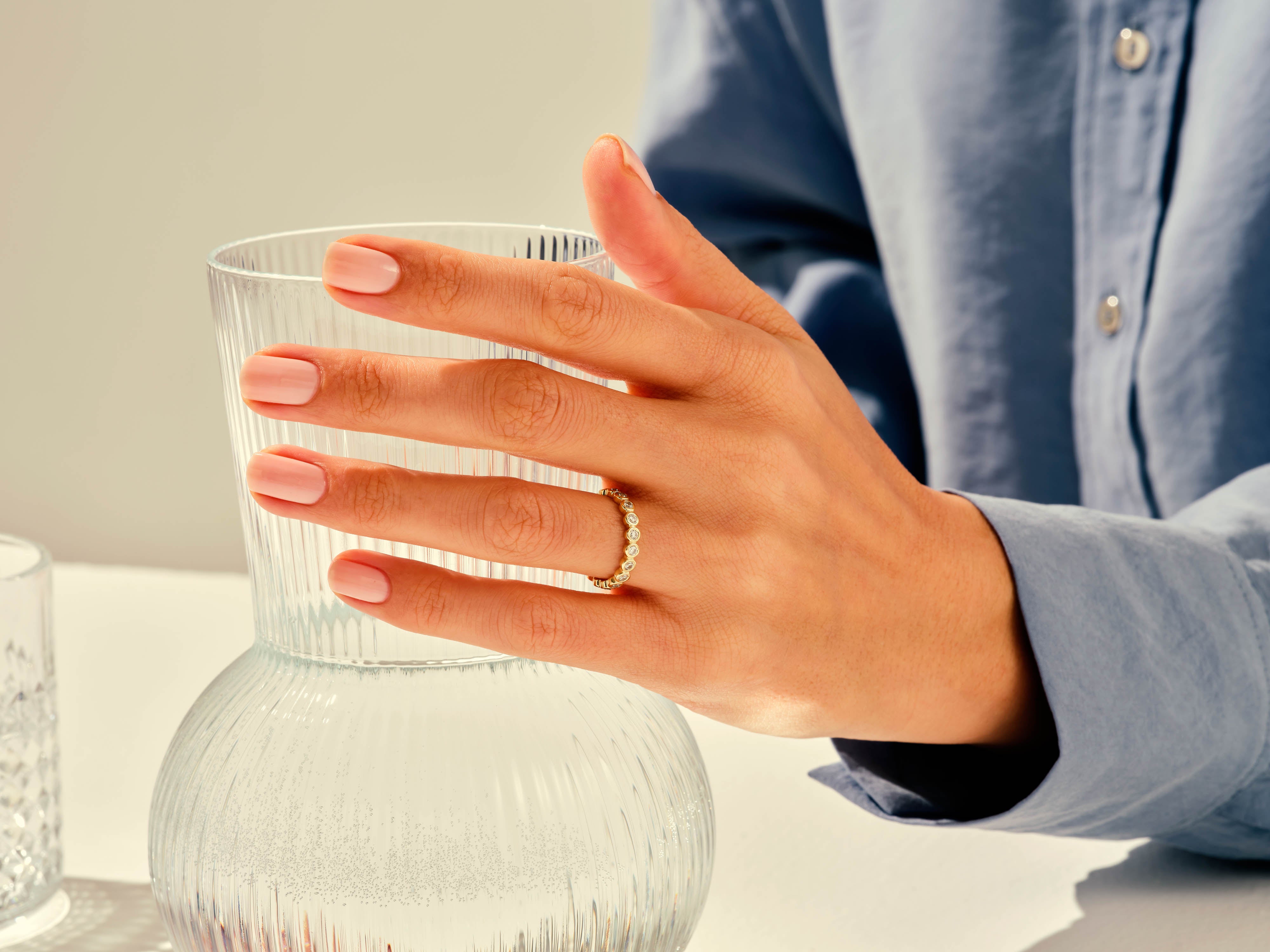 Diamond eternity ring on hand holding a glass