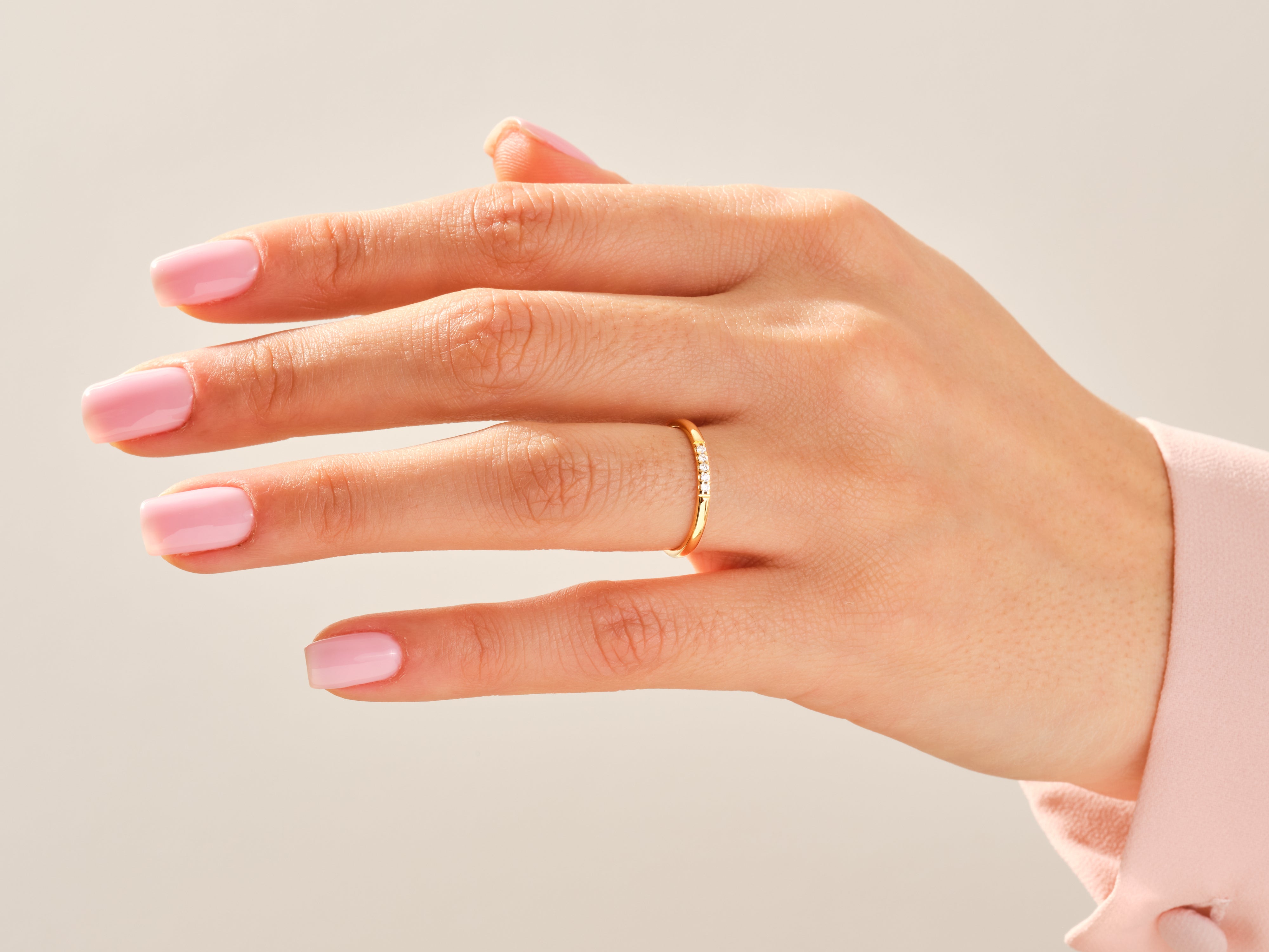 Delicate gold ring with small diamonds on a manicured hand