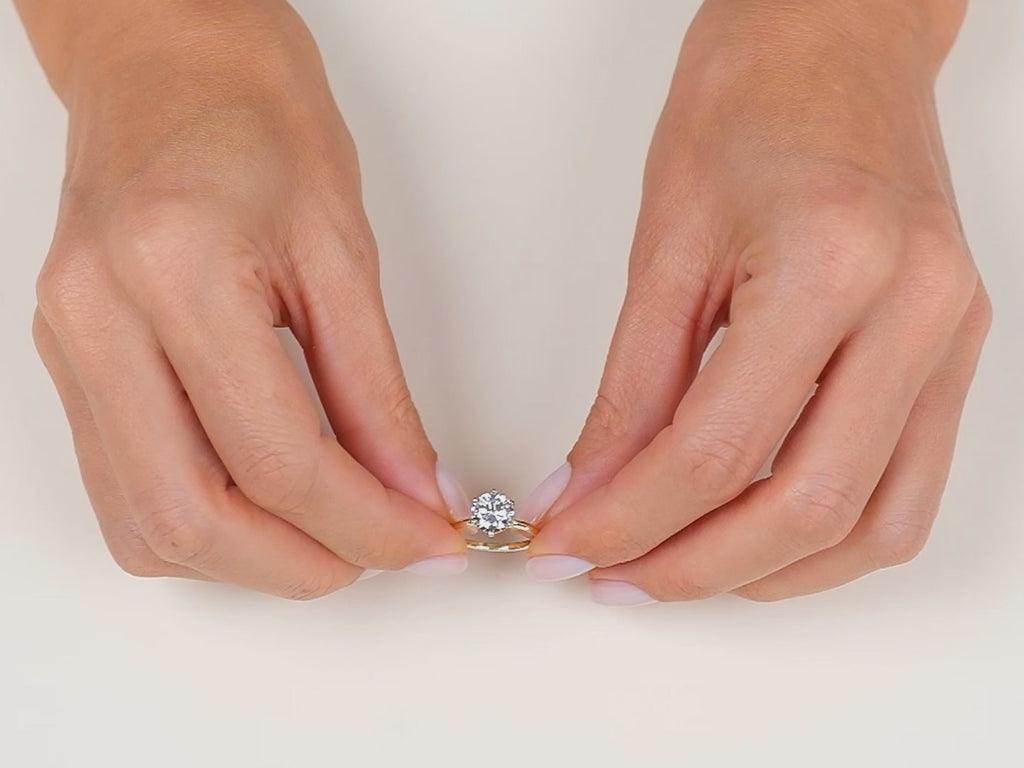 A video showcasing a hand wearing a yellow gold 6-prong solitaire round cut moissanite engagement ring 