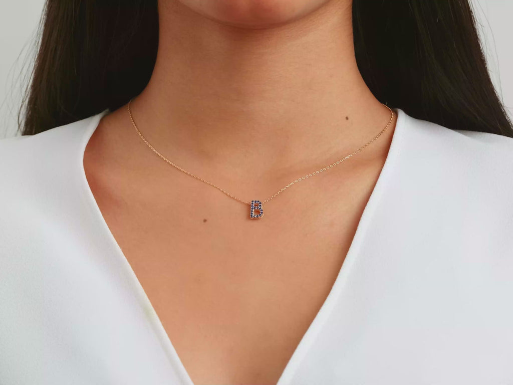 A video of a women model showing a yellow gold diamond initial letter necklace on her neck
