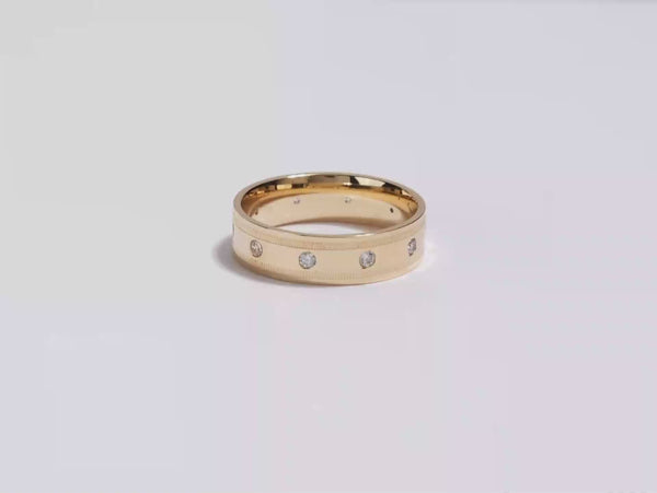 A video showing a yellow gold 6mm milgrain edged ten stone men's diamond wedding band spinning on a white background.